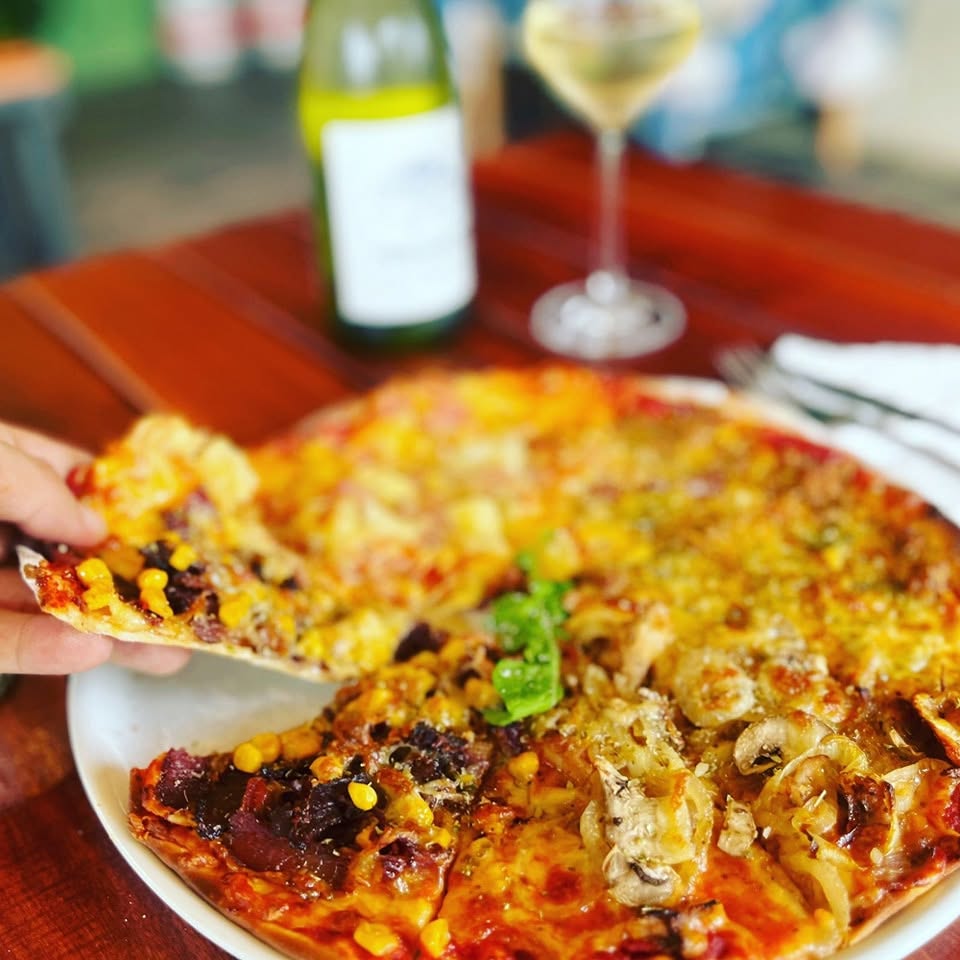 Freshly baked pizza topped with cheese and herbs at Café Crust